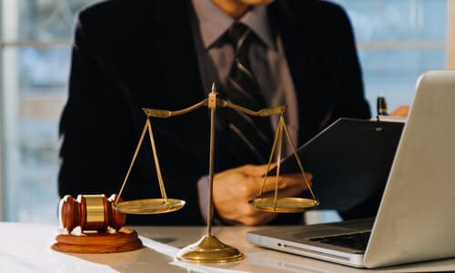 A driving accident lawyer in an office working on a case for a client on his laptop.