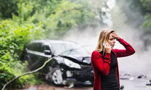 A woman calling for help after a serious car accident left her car off the road.