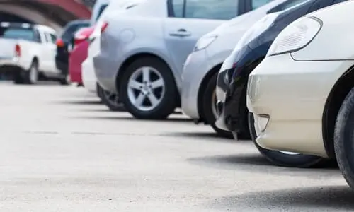 Cars sitting in a row in a parking lot waiting for their turn to be services.