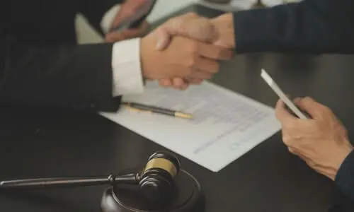 A diminished values claims lawyer shaking a client's hand after having made a successful claim.