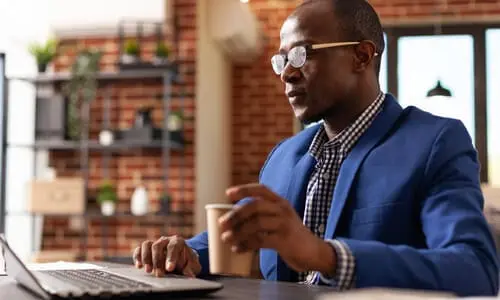 A well-dressed impaired driving lawyer having a cup of coffee while working on a client's case.