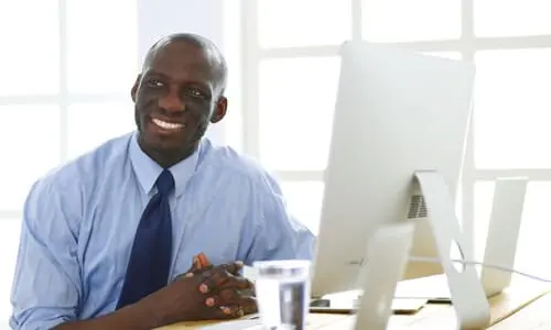 A lawyer in a brightly lit office smiling after a satisfied client leaves the room.
