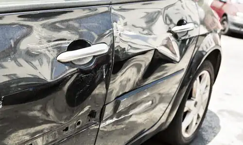 A damaged and dented car door after a sideswipe accident with another vehicle.