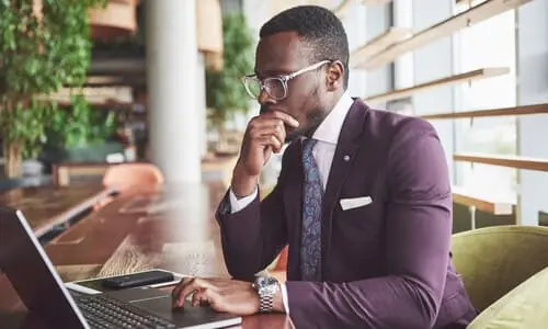 A teen accident lawyer in a purple suit working in a brightly lit lobby of his firm's building.