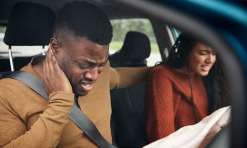 A couple in a car after an accident, having sustained injuries from their airbags deploying.