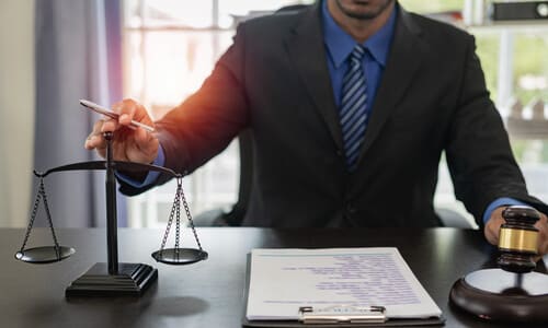 A Hartford amputation lawyer holding his hand over justice scales on his desk.