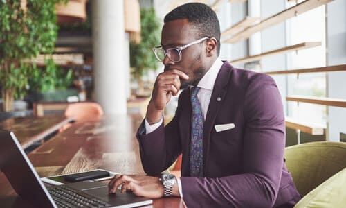 An aviation lawyer in a purple suit looking intently at his laptop while he works on a case.