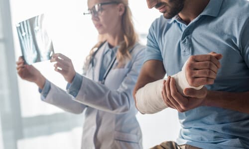 A doctor looking at an X-ray of a patient whose arm is in a cast.