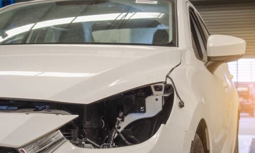 A car being taken in for maintenance after an accident caused by a defective headlight.