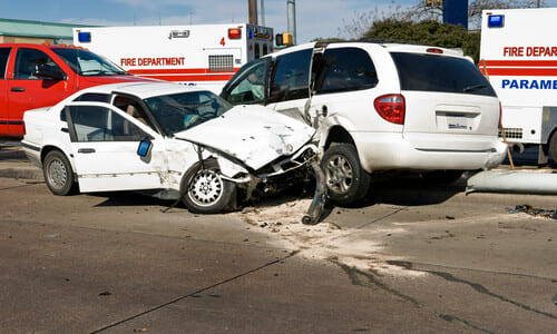 A collision between two white vehicles after one of them failed to follow a red traffic signal.