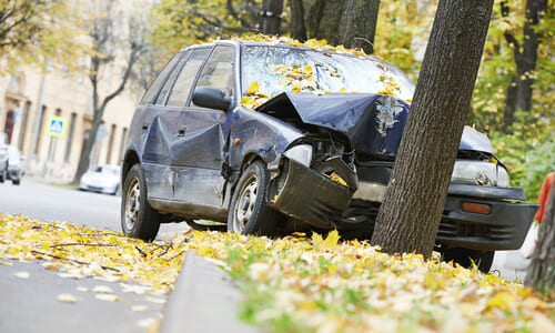 A blue hatchback after colliding with a tree due to a fatigued driver at the wheel.