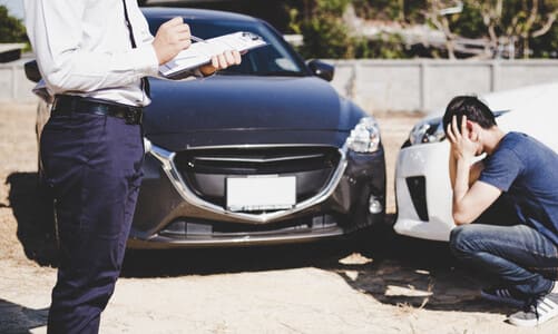 A lawyer and his client looking evaluating the damage dealt to the latter's vehicle.