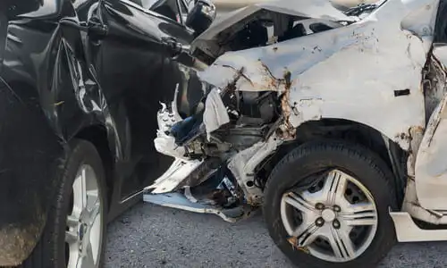 A collision between a white and a black vehicle after the latter attempted to execute a left turn.