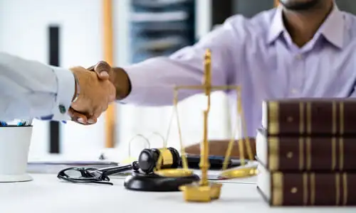 A red light accident lawyer shaking his client's hand in his office after coming to an agreement to work together.