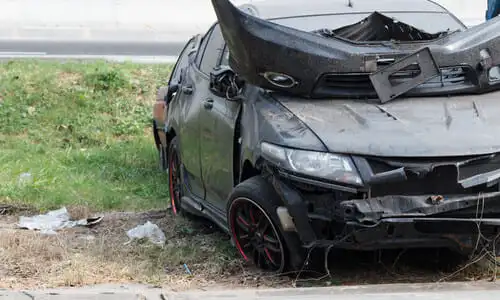 A black car having crashed off-road after the driver lost control of the vehicle.