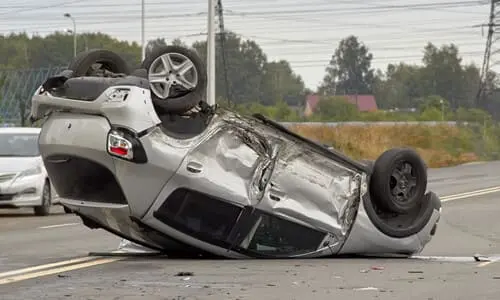 A vehicle turned upside-down and stuck in place after a rollover accident on a highway.