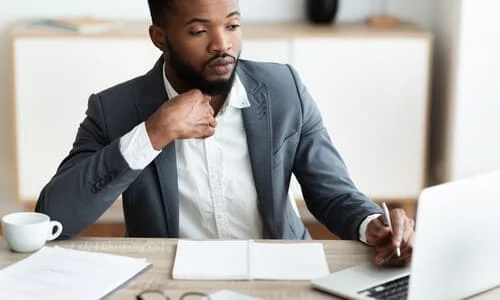 Are Personal Injury Settlements Taxable? A personal injury lawyer having a cup of coffee while working on a laptop to maximize a claim for a client.