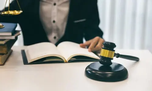 A personal injury lawyer pointing at a specific line in a book while working at a desk.
