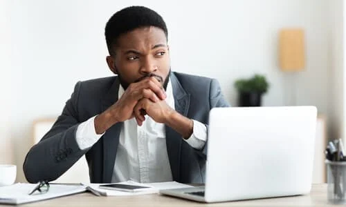 A lawyer with hands clasped in front of his mouth as he strategizes an approach for a client's case.