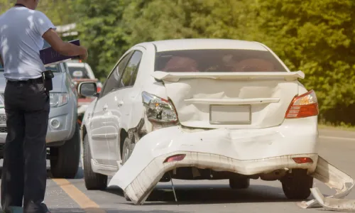 A driver looking over papers as he documents damage to his vehicle caused by an uninsured motorist accident.
