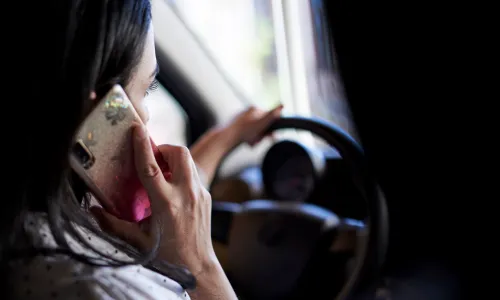 An over-the-shoulder shot of a driver on a phone call while driving a car.