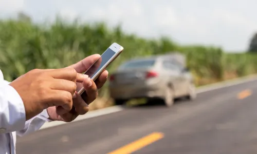 A driver calling for legal assistance on his phone after an accident with an uninsured driver.