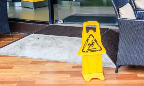 What if I Slip and Fall on a Rental Property? A caution sign on the floor of a cafe warning of potential slips and falls.